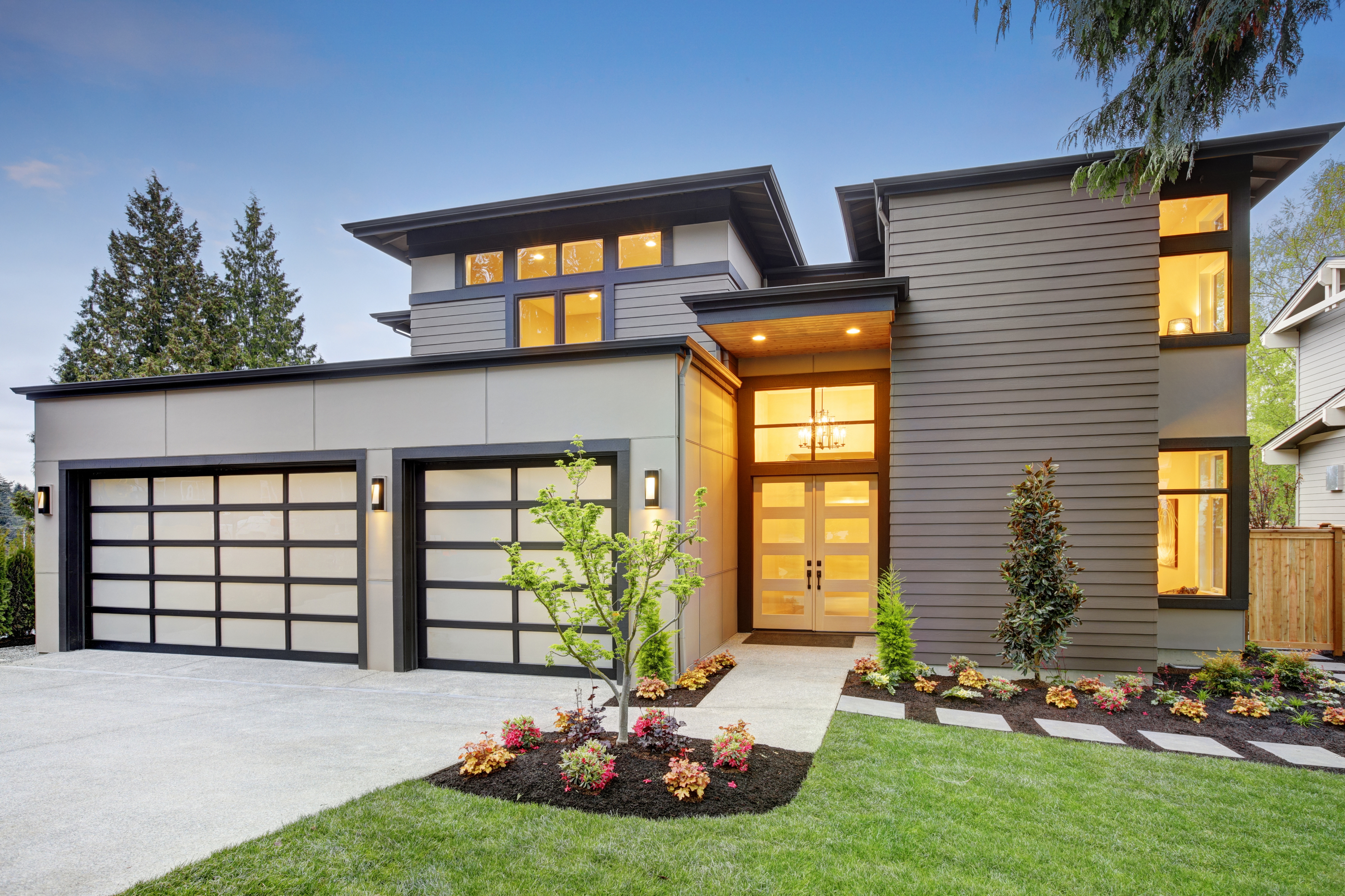 A modern house with a garage and cobblestone driveway.