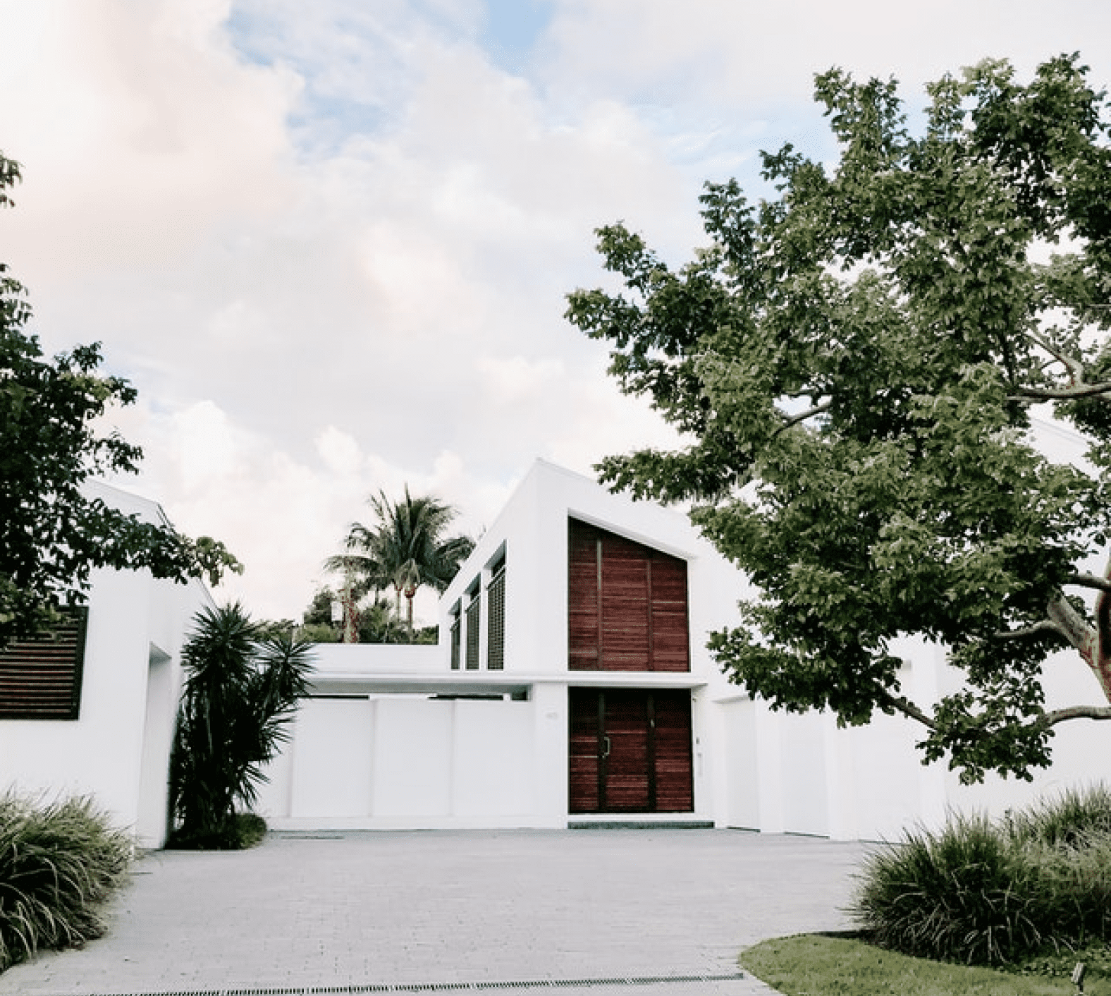 A modern ivory white house a gray tiled garage ramp.